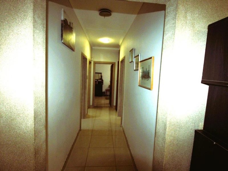 A functional residential hallway featuring tiled flooring and central ceiling lighting, providing access to adjacent rooms.