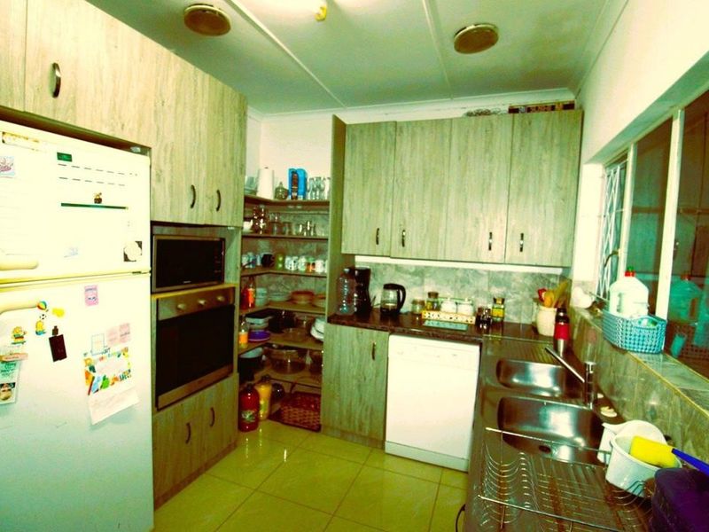 A functional kitchen featuring wood-look cabinetry, built-in oven and microwave, double stainless steel sink, and tiled flooring.