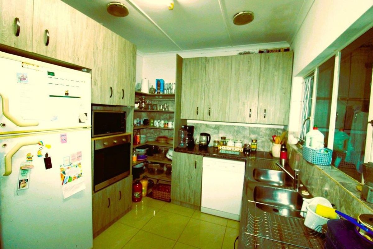 A functional kitchen featuring wood-look cabinetry, built-in oven and microwave, double stainless steel sink, and tiled flooring.