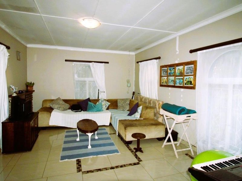 A living room featuring tiled flooring and a tiled ceiling, providing a functional space with potential for cosmetic updates.