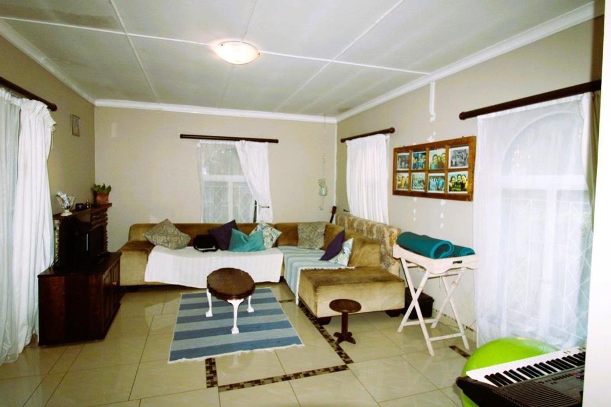 A living room featuring tiled flooring and a tiled ceiling, providing a functional space with potential for cosmetic updates.
