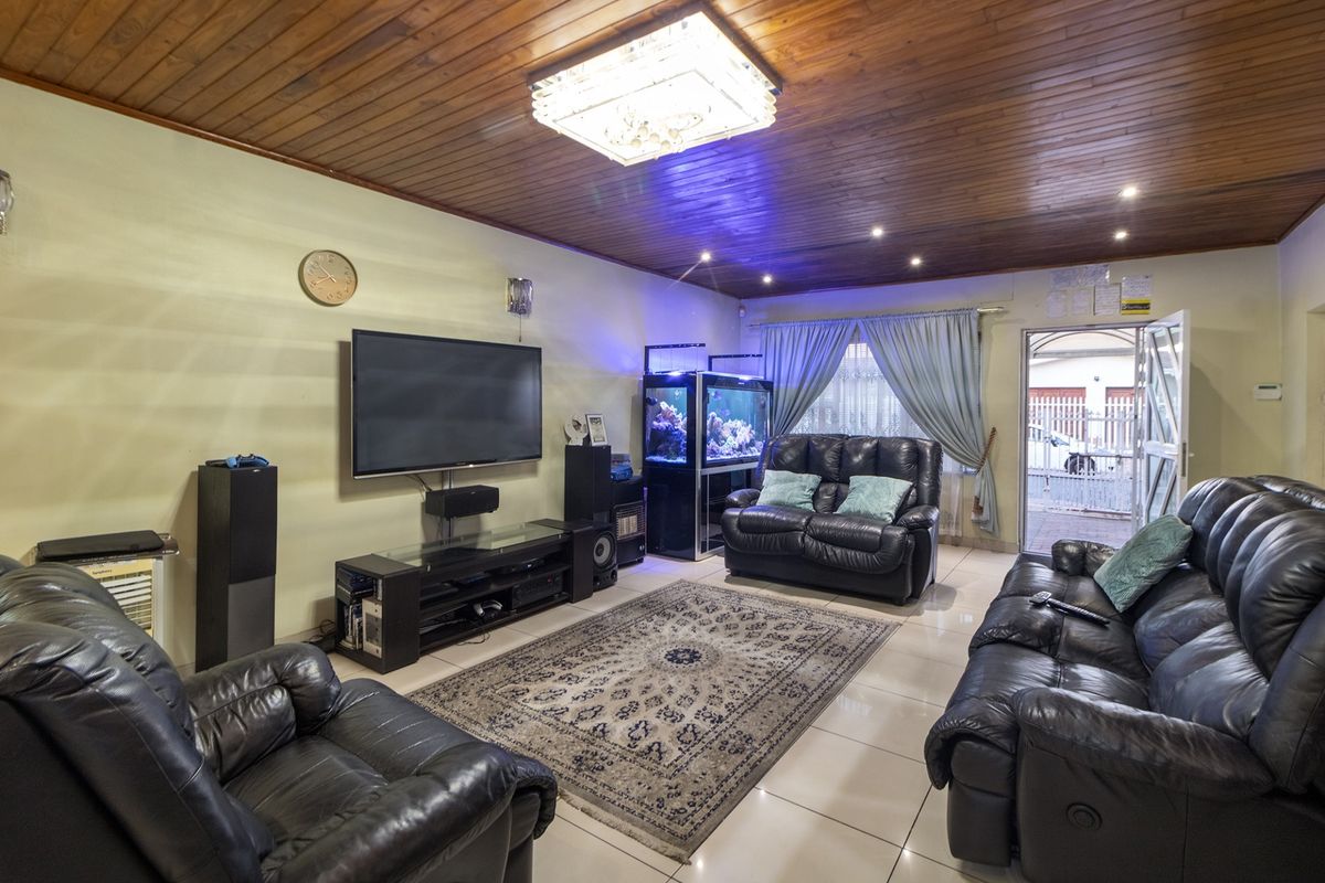 A spacious living room featuring a warm timber-clad ceiling, tiled flooring, and recessed lighting, providing a comfortable and functional family entertainment area.