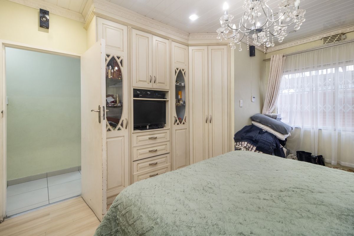 A bedroom featuring extensive built-in cabinetry with integrated shelving, crown molding, and tiled flooring, offering ample storage space.