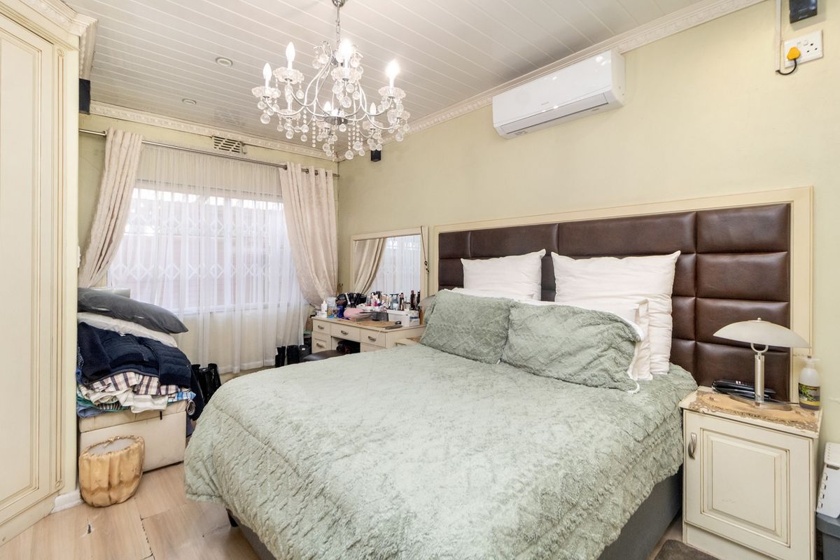 A well-appointed bedroom featuring a paneled ceiling, crown molding, built-in wardrobe, and a wall-mounted split-system air conditioner.