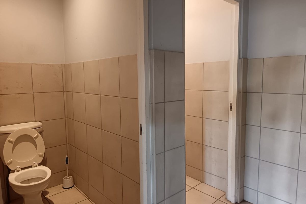 Commercial restroom facility featuring tiled walls and floors with a partitioned toilet cubicle layout.