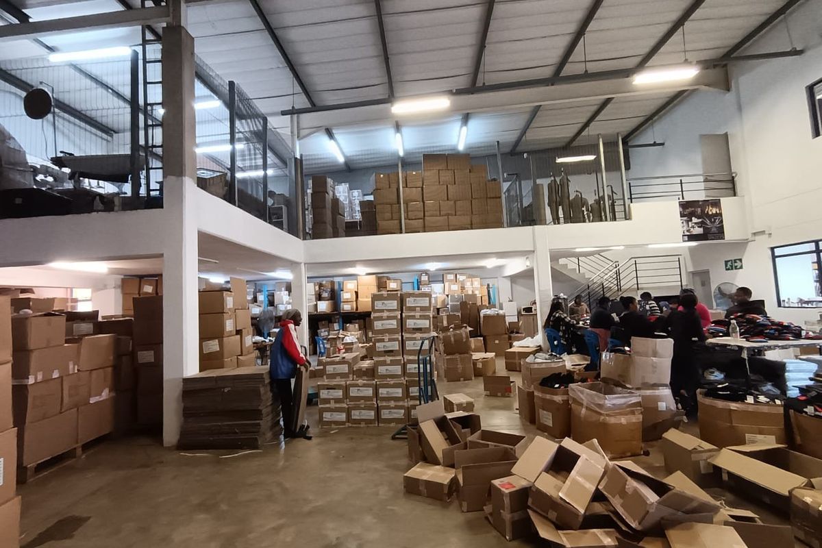 Spacious commercial warehouse or industrial utility space featuring a mezzanine level, exposed steel roof trusses, and durable concrete flooring.