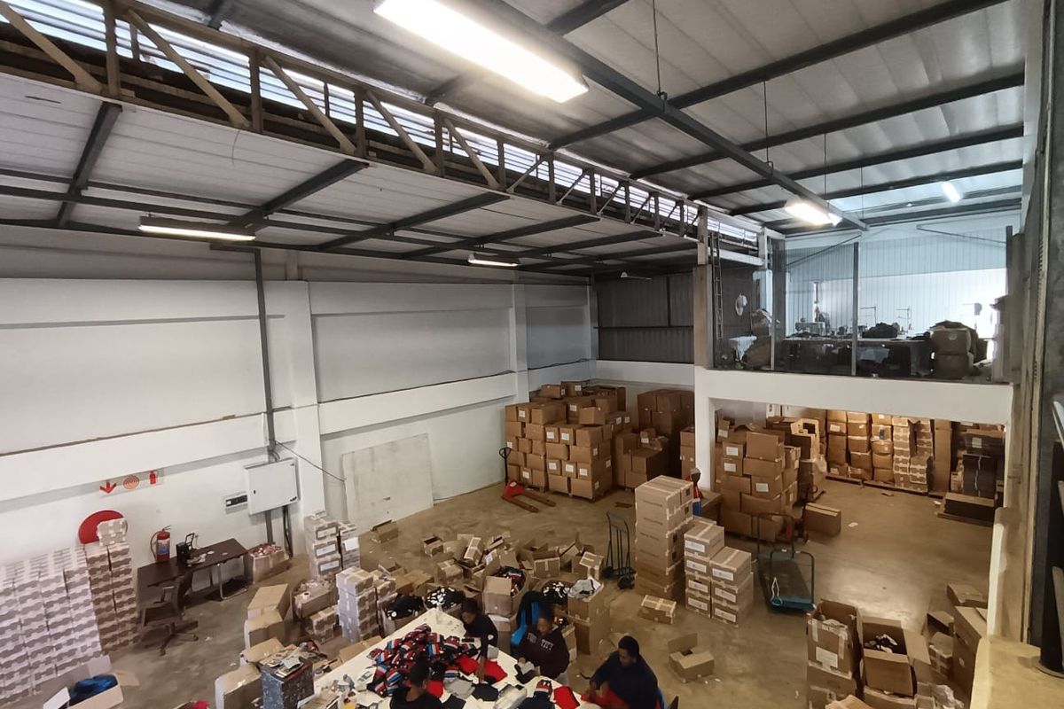 Spacious commercial warehouse featuring high ceilings with exposed steel trusses, mezzanine level, and functional open-plan floor space suitable for industrial or storage operations.