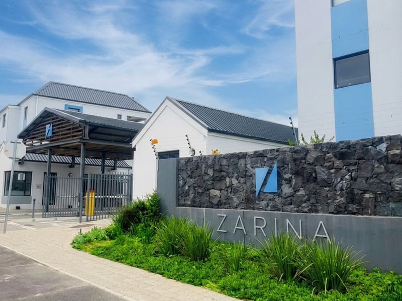 Front entrance view of the Zarina apartment complex featuring a stone-clad signage wall, secure gated access, and well-maintained paved walkways.
