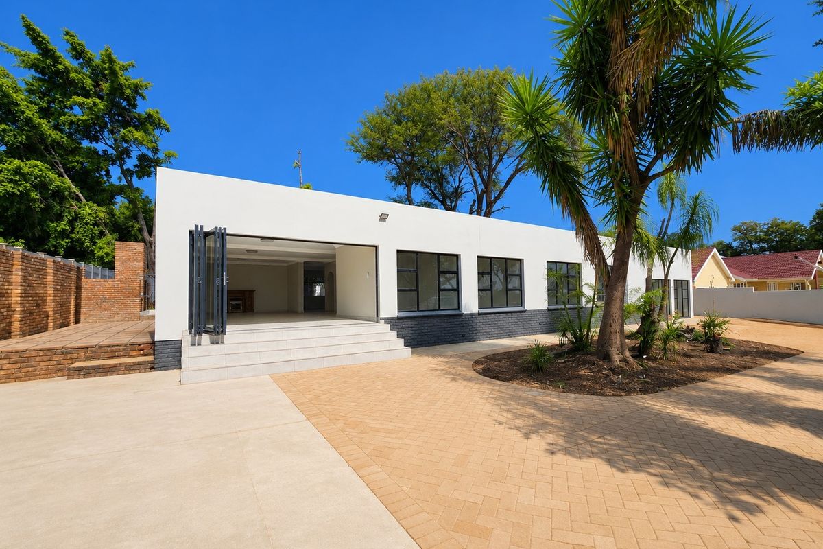 Rear view of the property featuring a paved courtyard, tiled patio steps, and modern bi-fold doors leading into the main living area.