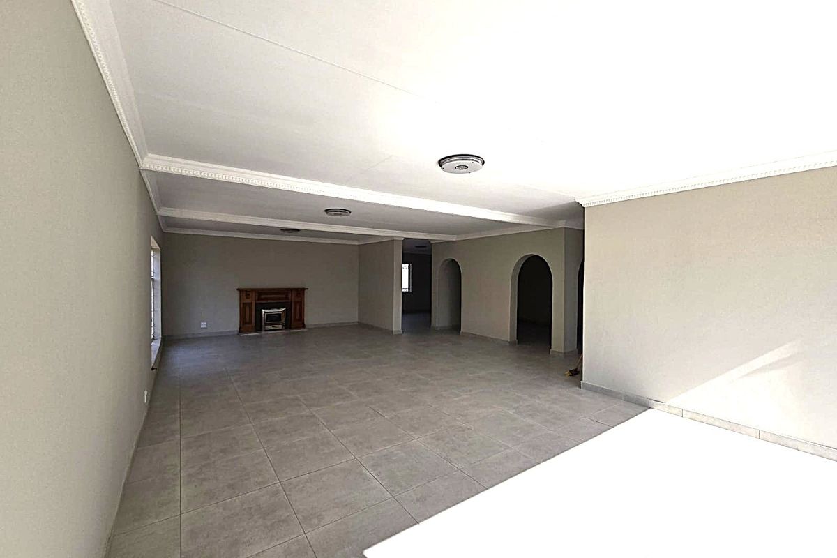 Spacious, open-plan living area featuring neutral tiled flooring, a built-in fireplace, and decorative archways leading to adjacent rooms.
