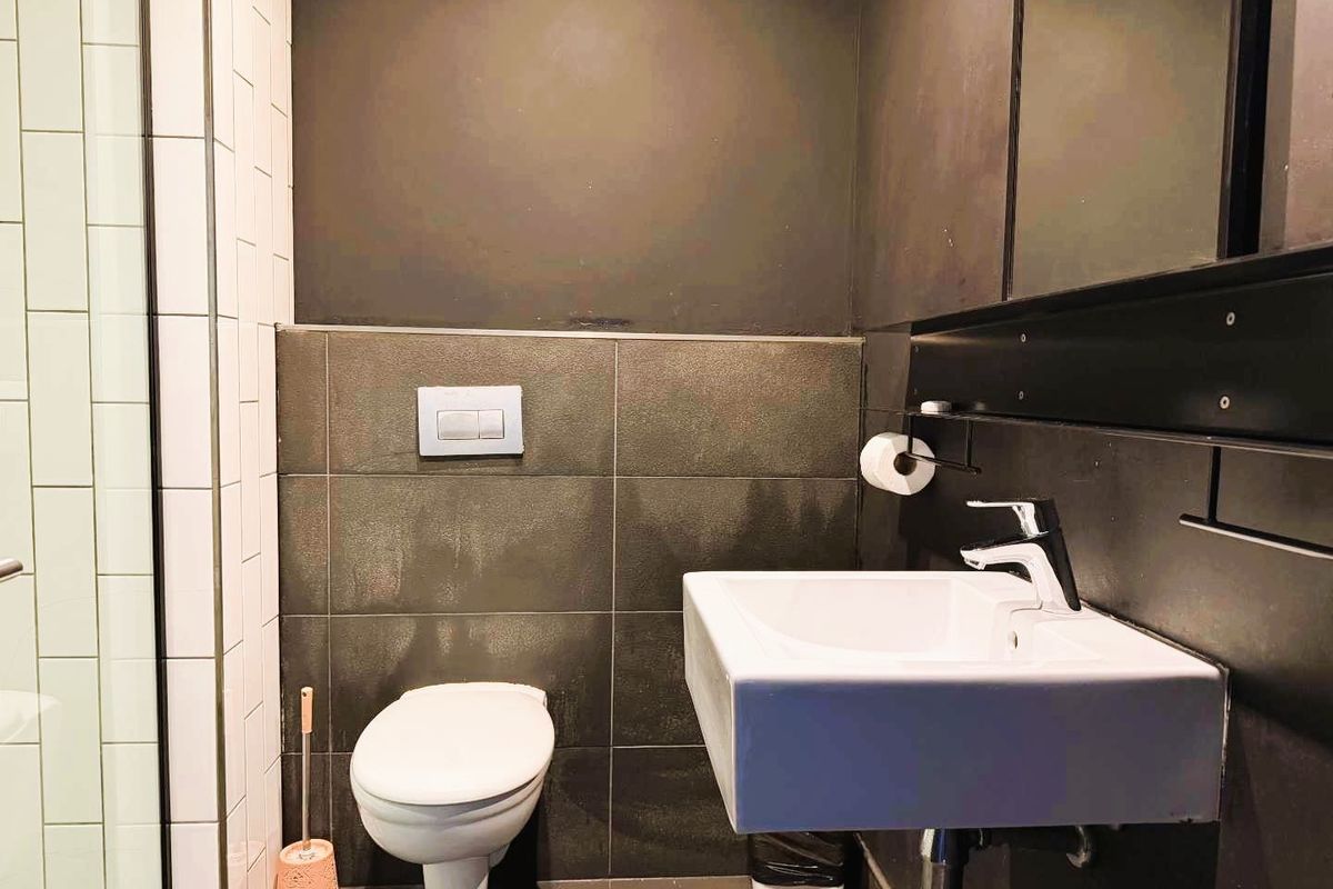 Modern bathroom featuring a wall-mounted toilet with concealed cistern, a sleek wall-mounted basin with chrome mixer tap, and a tiled shower enclosure.