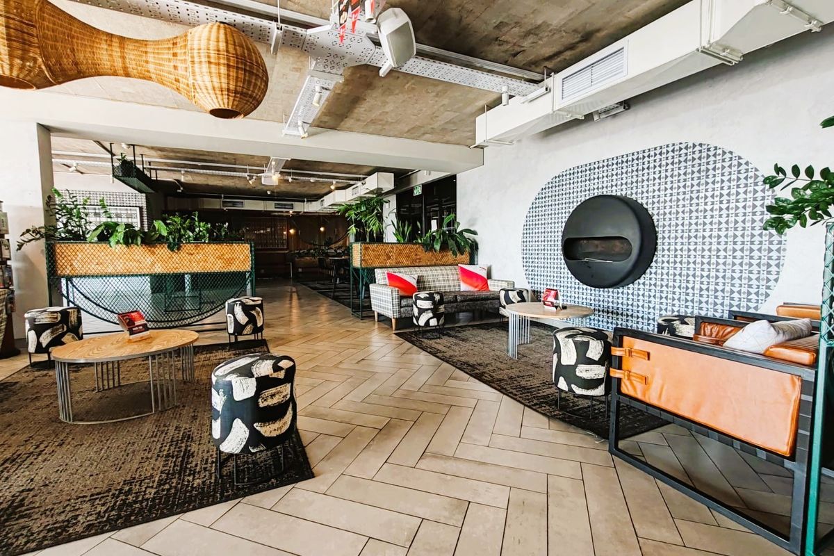 A modern, industrial-style living area featuring an exposed concrete ceiling, herringbone tile flooring, and a unique circular wall-mounted fireplace.