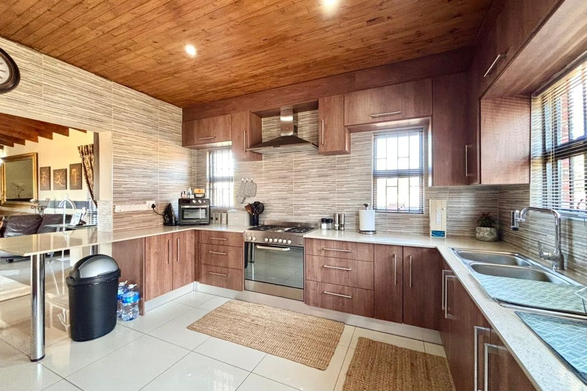 Modern kitchen featuring warm wood-paneled ceilings, stone countertops, built-in stainless steel appliances, and a convenient breakfast bar area.