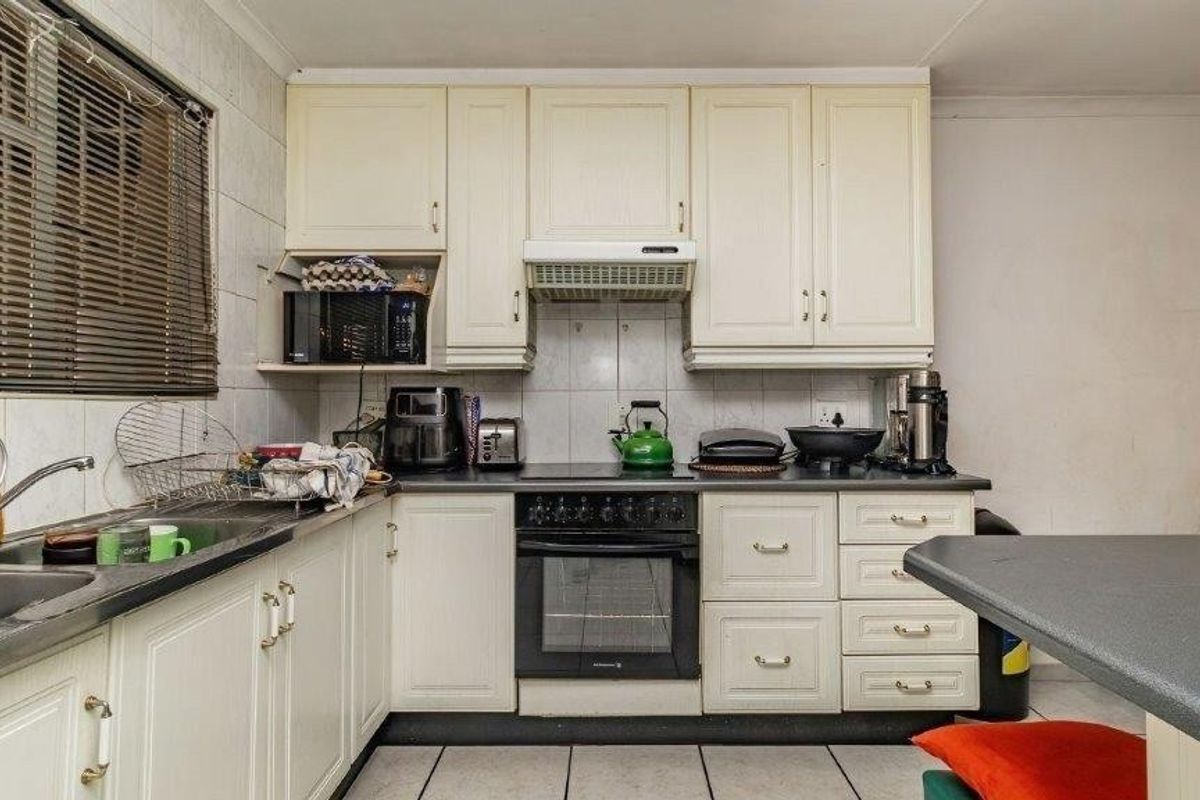 A functional kitchen featuring built-in cabinetry, laminate countertops, a built-in oven with hob, and tiled flooring, offering potential for modernization.