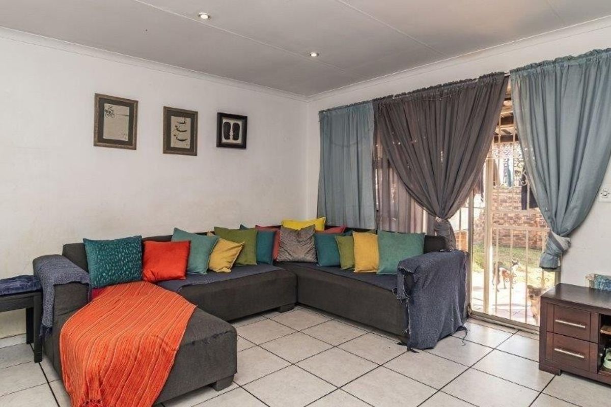 A living room featuring tiled flooring, recessed downlights, and a sliding glass door providing access to the outdoor area.