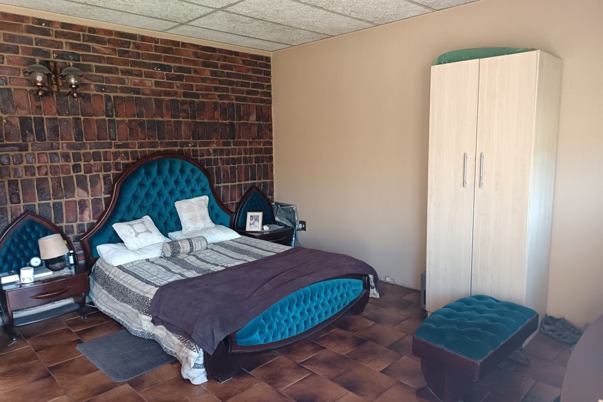Bedroom featuring an exposed brick accent wall, tiled flooring, and acoustic ceiling tiles.