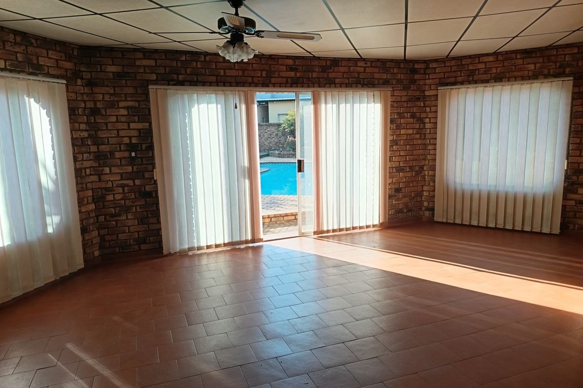 Spacious living area featuring exposed brick walls, tiled flooring, and a sliding glass door providing direct access to the outdoor pool area.