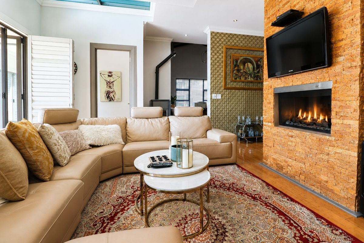 Spacious living room featuring a striking stone-clad fireplace, hardwood flooring, and a large skylight that fills the area with natural light.
