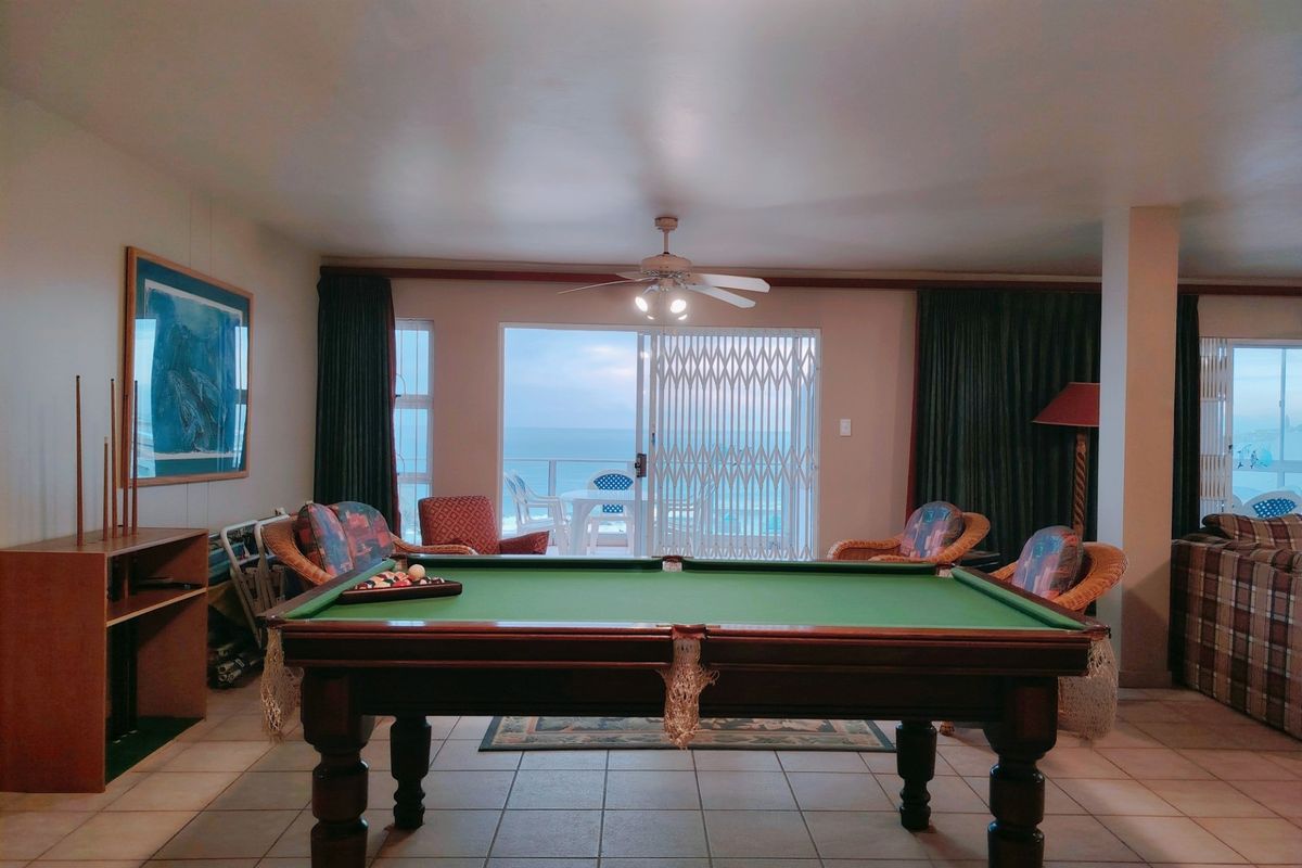 Spacious living area featuring tiled flooring, a ceiling fan, and sliding glass doors leading to a balcony with ocean views.