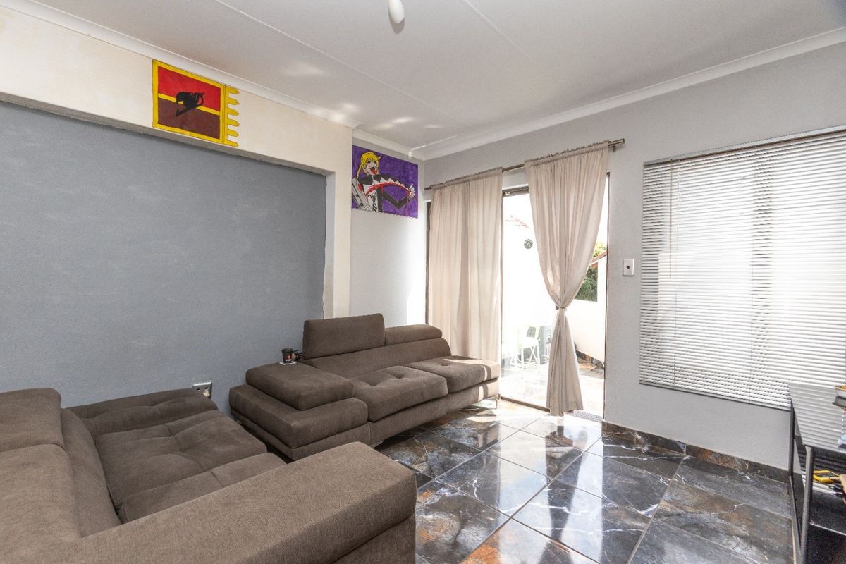 A living room featuring dark marble-effect floor tiles, cove cornicing, and a sliding glass door providing access to an outdoor area.