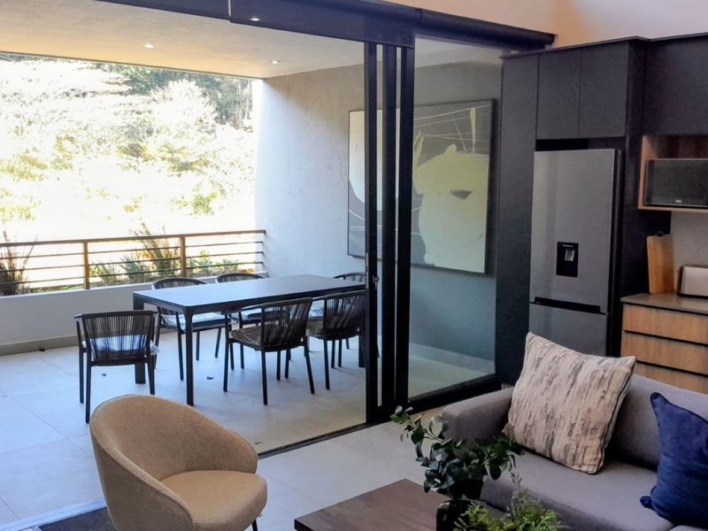 Modern open-plan living area featuring a sleek kitchen with built-in appliances and large sliding doors opening onto a covered patio.