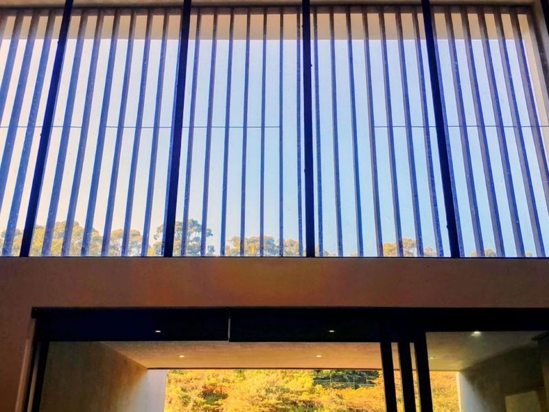 Spacious living area featuring impressive double-volume windows that provide abundant natural light and views of the surrounding greenery.