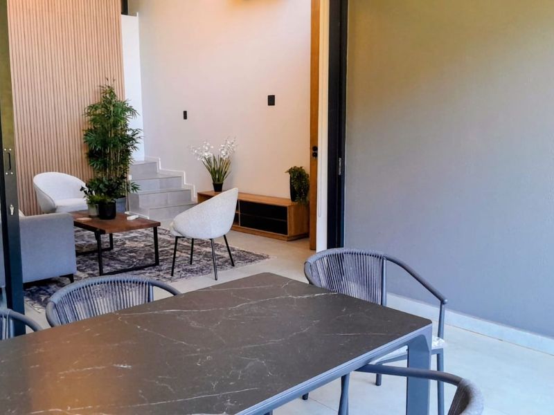 A modern covered patio area featuring large sliding glass doors, slatted timber wall accents, and tiled flooring, seamlessly connecting to the interior living space.