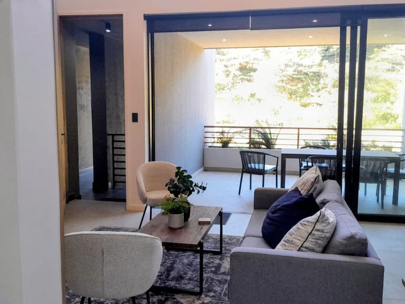 Modern open-plan living area featuring large sliding glass doors that open onto a private balcony, creating a seamless indoor-outdoor flow.
