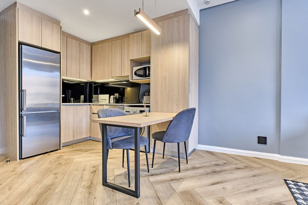 Modern open-plan kitchen featuring light oak cabinetry, herringbone wood flooring, and integrated appliances, creating a sleek and functional living space.