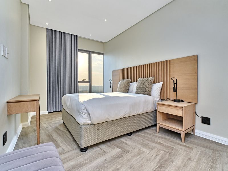 Modern bedroom featuring herringbone wood-look flooring, recessed lighting, and a custom timber headboard with integrated bedside storage.