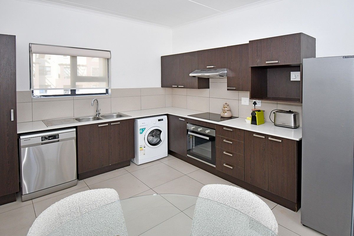 Modern kitchen featuring dark wood cabinetry, stone countertops, integrated appliances, and tiled flooring, offering a clean and functional workspace.