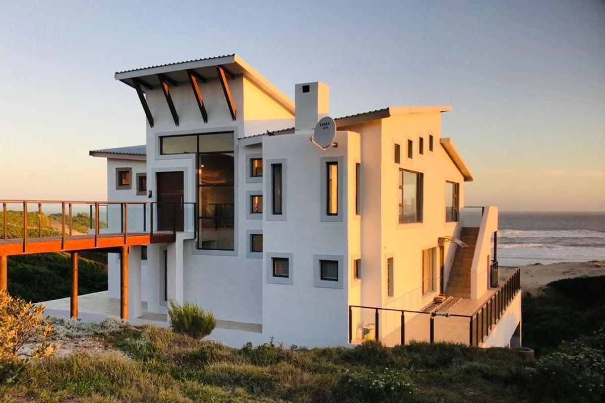 Modern multi-level coastal residence featuring a raised timber walkway, expansive balconies, and contemporary architectural design with direct ocean views.