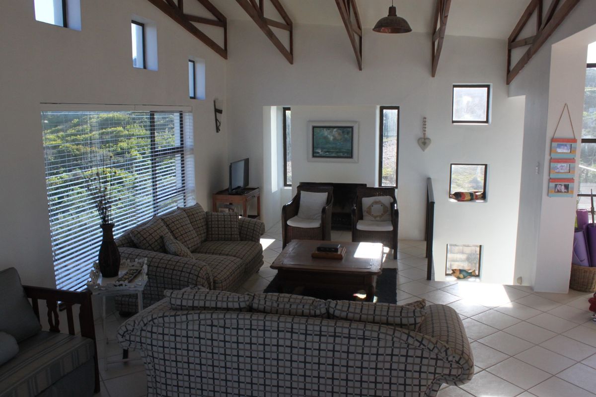 Spacious living room featuring high vaulted ceilings with exposed timber trusses, tiled flooring, a cozy fireplace, and abundant natural light from multiple windows.