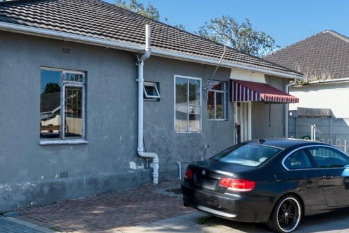 Rear exterior view of the house featuring a paved driveway, tiled roof, and a small awning over the entrance.