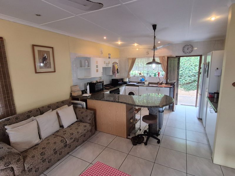 Open-plan kitchen and living area featuring a granite breakfast bar, tiled flooring, and direct access to the rear garden.