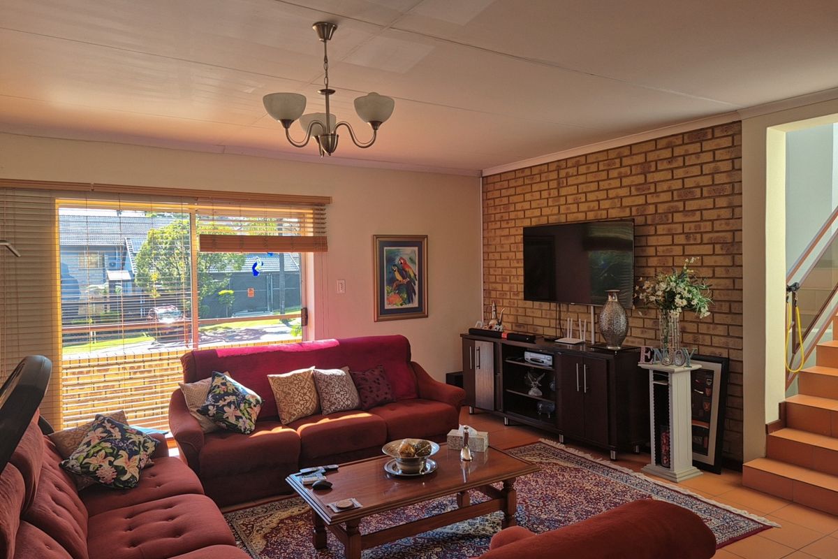 Spacious living room featuring an exposed brick accent wall, tiled flooring, and direct access to an outdoor area via a sliding glass door.