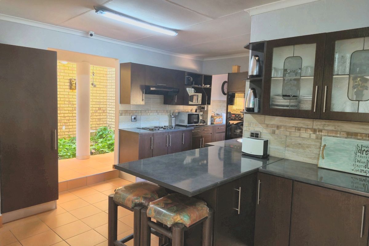 Functional kitchen featuring dark wood cabinetry, stone countertops, a breakfast bar, and direct access to an outdoor patio area.