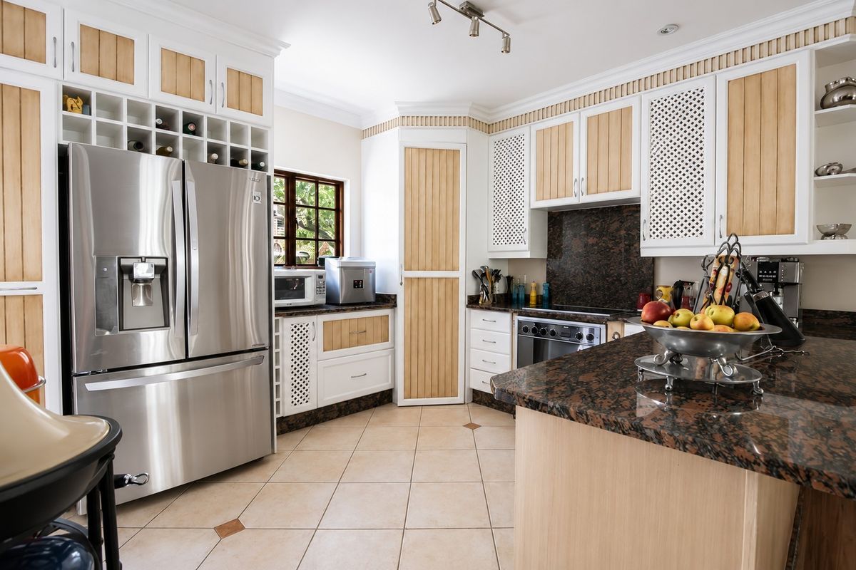 A well-appointed kitchen featuring granite countertops, extensive built-in cabinetry with integrated wine storage, and ceramic tile flooring.