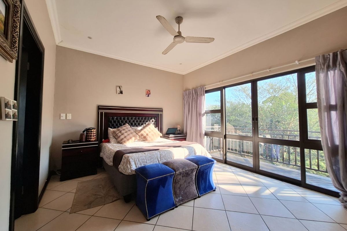 Spacious bedroom featuring tiled flooring, a ceiling fan, and large sliding glass doors providing natural light and direct access to a balcony.