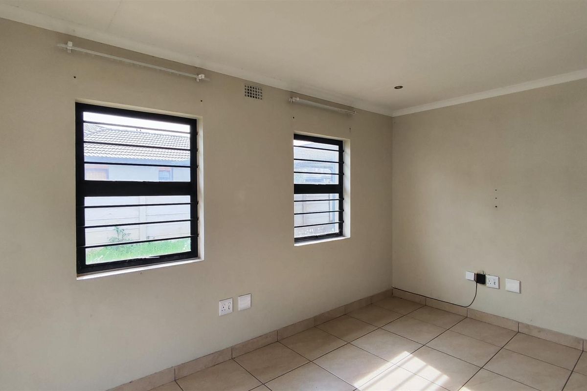 An empty bedroom featuring tiled flooring, security bars on the windows, and recessed downlights, providing a neutral canvas for personalization.