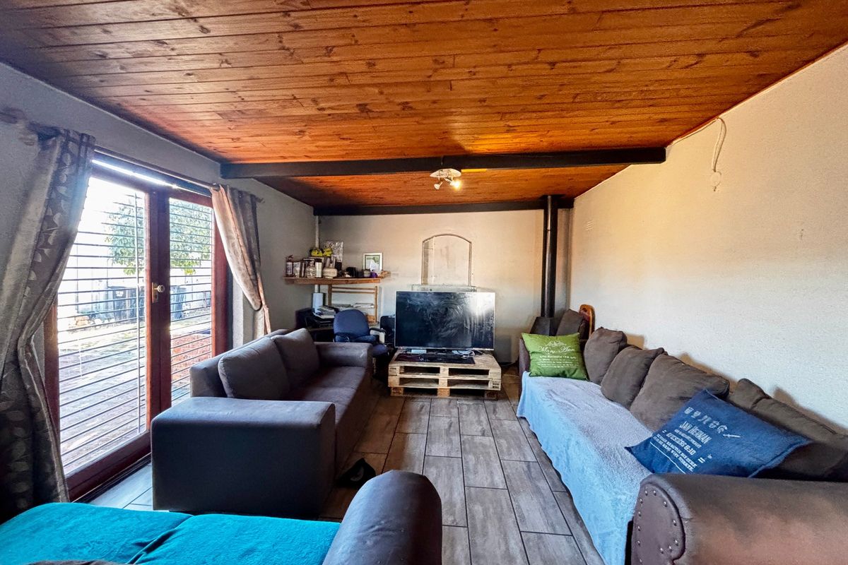 Living room featuring a wood-paneled ceiling, tiled flooring, and a wood-burning fireplace with direct access to the outdoor area via sliding glass doors.
