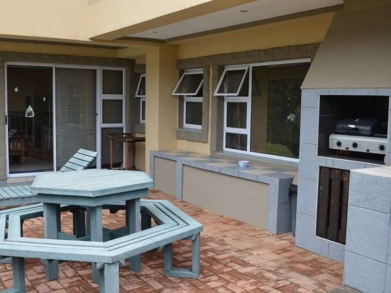 Covered outdoor patio featuring a built-in braai, tiled flooring, and direct access to the interior living space through sliding glass doors.