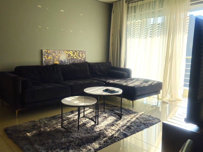 A living room featuring tiled flooring and a large sliding glass door with curtains, providing natural light to the space.