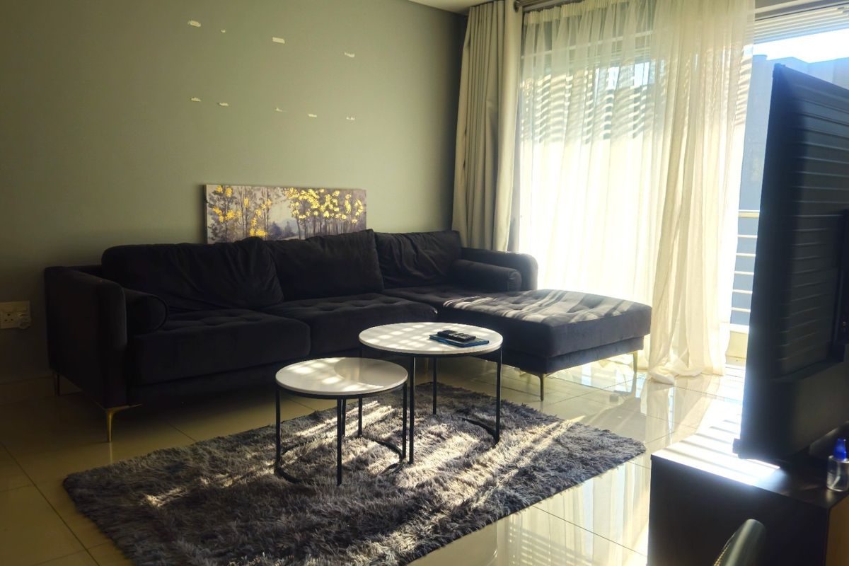 A living room featuring tiled flooring and a large sliding glass door with curtains, providing natural light to the space.
