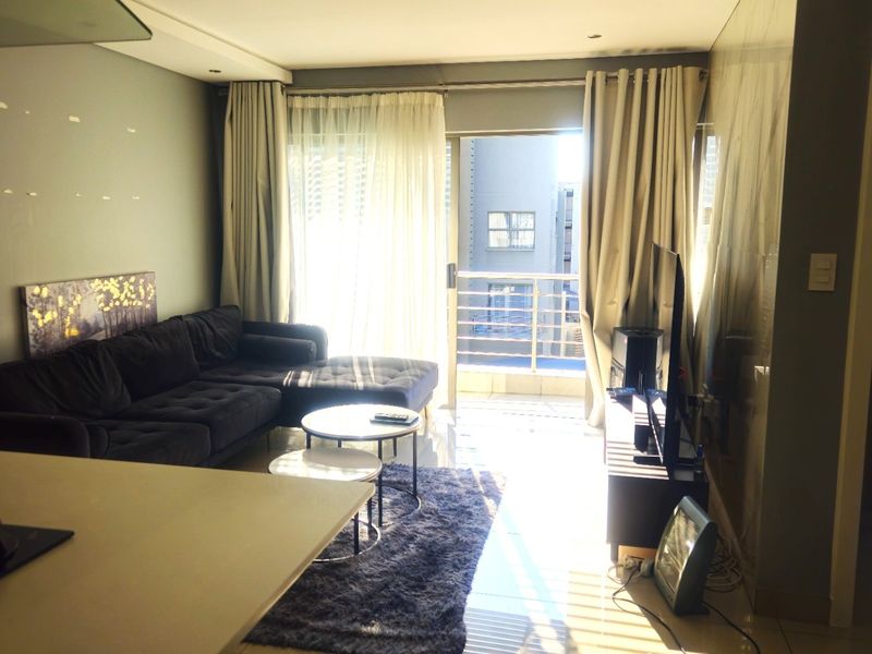 Open-plan living area featuring tiled flooring and direct access to a private balcony through a sliding glass door.