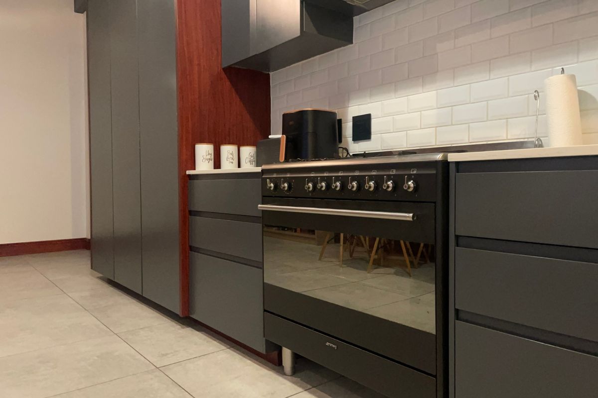 Modern kitchen featuring dark grey cabinetry, a professional-style freestanding oven, extractor fan, and a clean white subway tile backsplash.