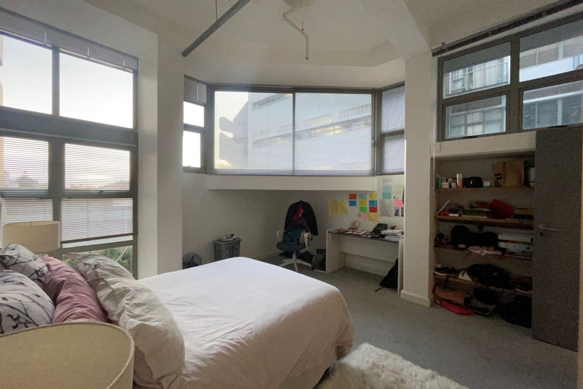 Spacious bedroom featuring large windows, built-in shelving, and carpeted flooring, offering a bright and functional living space.