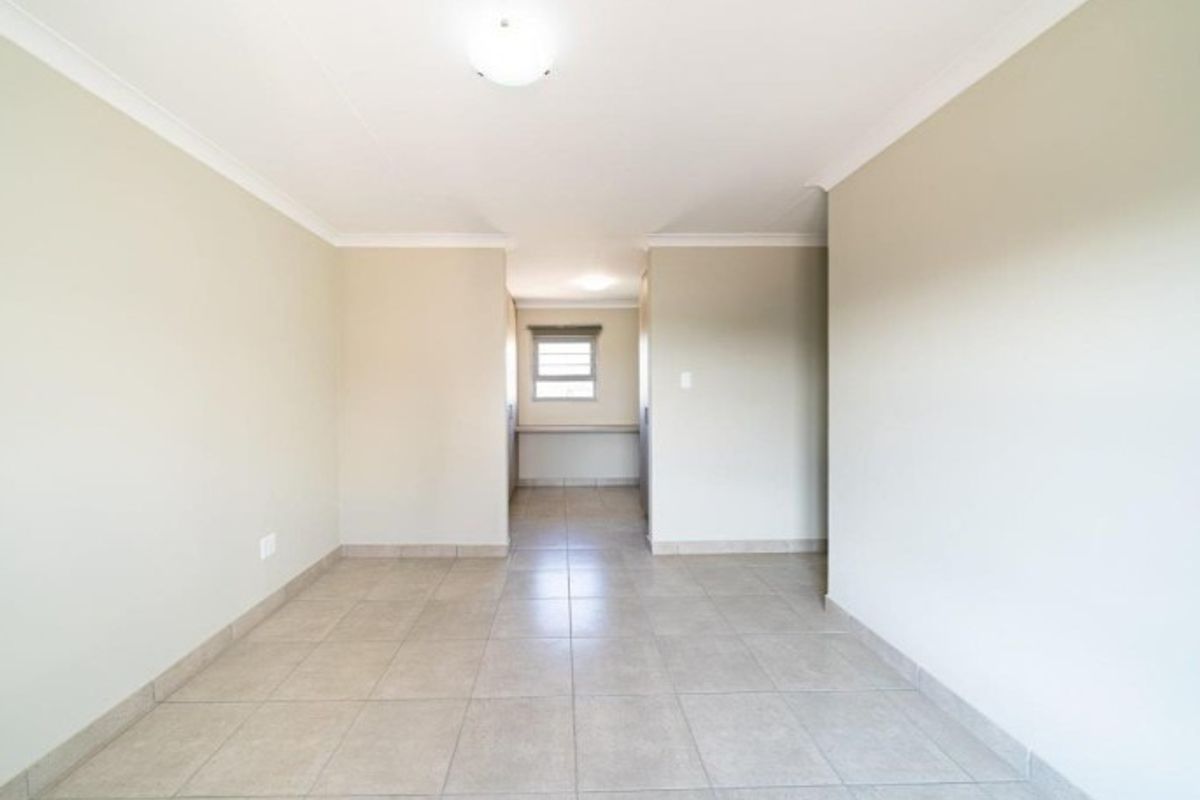 A bright, empty living area featuring neutral tiled flooring and clean walls, offering a versatile space ready for personalization.