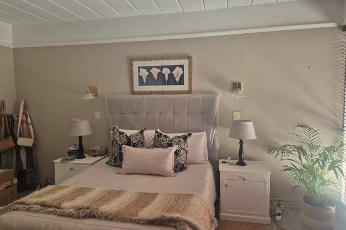 A well-maintained bedroom featuring a neutral color palette, tongue and groove ceiling detail, and wall-mounted lighting fixtures.