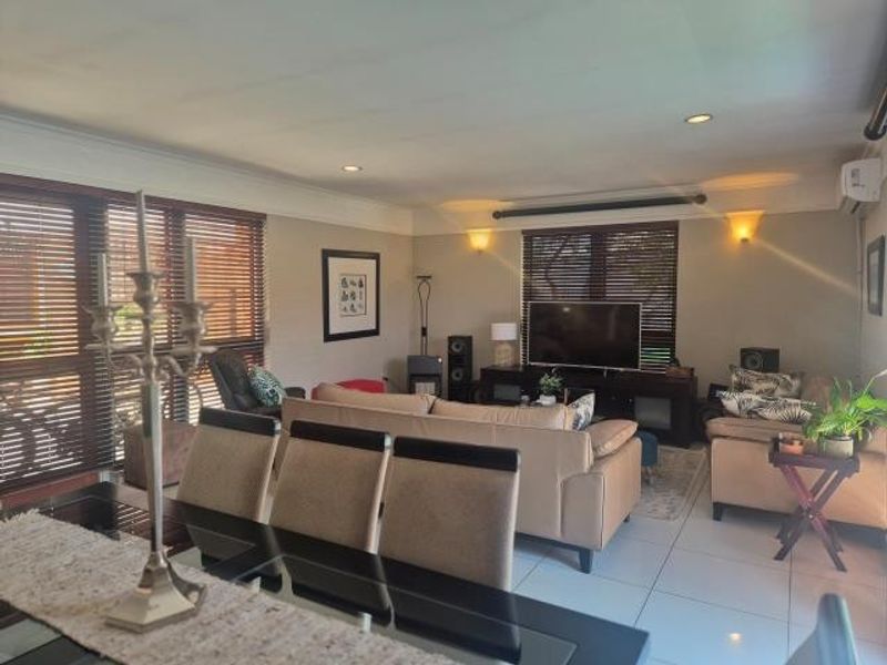 Spacious open-plan living and dining area featuring tiled flooring, recessed lighting, and large windows with venetian blinds.